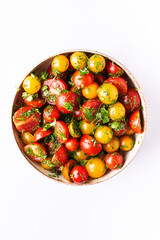 Bright juicy salad with colorful cherry tomatoes and aromatic herbs on white marble table top view. Healthy vegan food concept.
