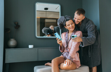 A couple shares a digital moment, leaning in with curiosity over their phones in a chic lounge.