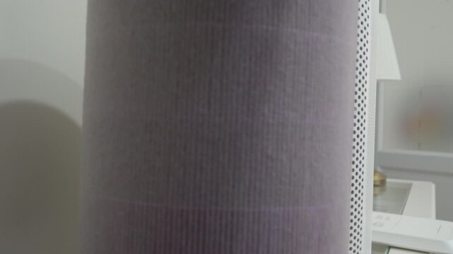 A close-up view of a heavily dust-laden, pleated purple filter inside a white air purifier housing. This crucial component is ready for cleaning or replacement to restore optimal air quality.