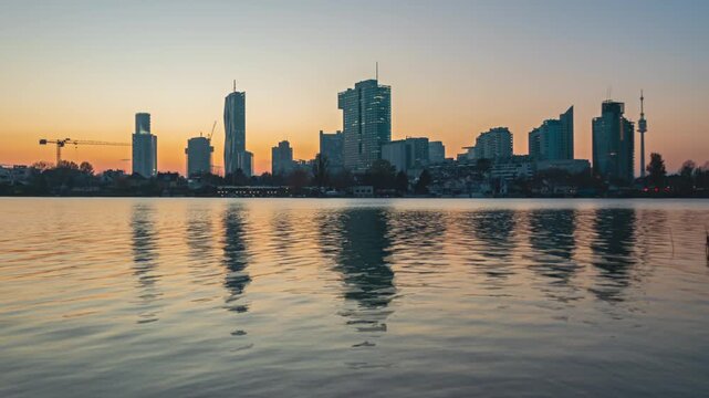Day to night to day time lapse Skyline of Donau City (Donaustadt), Vienna business district. Reflection in calm lake.