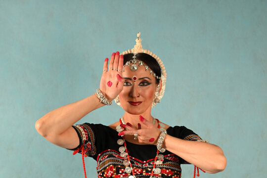An Indian dancer girl poses in a dance pose in a studio on a blue background