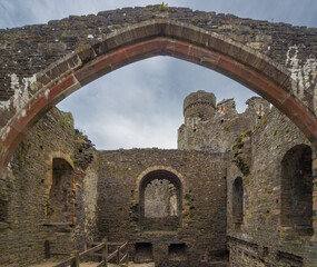 The weathered interior ruins of a famous Welsh castle seen through a chapel archway (Conwy, Wales, United Kingdom)