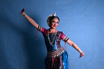 Indian dancer in the studio on a blue background in a dance pose