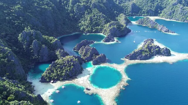 A 4K aerial drone shot rising and slowly pulling back over Twin Lagoon in Coron, Palawan. The video captures crystal-clear turquoise water, visible coral reefs and the dramatic limestone formations