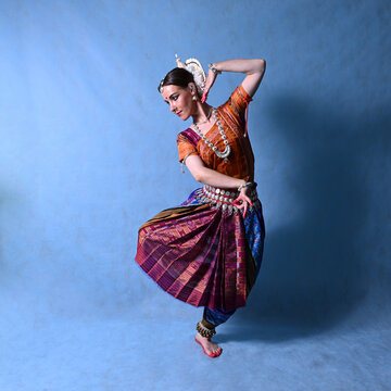 Indian dancer in the studio on a blue background in a dance pose
