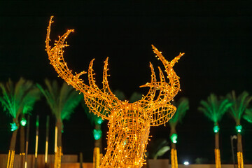 Illuminated deer sculpture with palm trees at night
