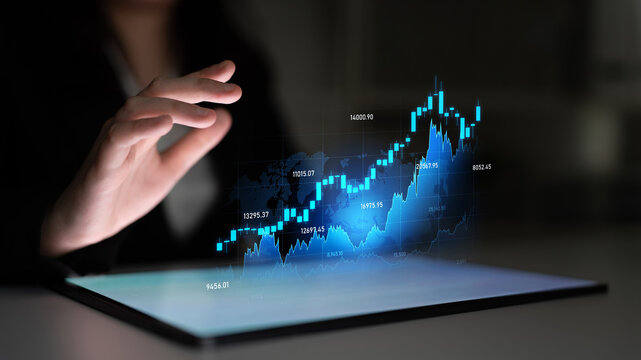 A businesswoman engages with holographic stock market data on a tablet, illustrating modern technology role in finance and investment strategies in a sleek office setup. Scalp - Powered by Adobe