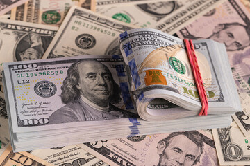 Close Up Stack of New One Hundred US Dollar Bills on Scattered Money Background