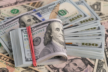 Close Up Stack of New One Hundred US Dollar Bills on Scattered Money Background