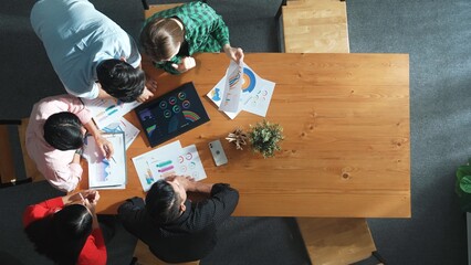 Top down aerial view of smart business people analyze data together at meeting. Group of business team working together and looking at financial chart at tablet placed on meeting table. Convocation.