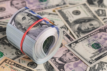 Close Up Roll of One Hundred US Dollar Bills Secured with Red Rubber Band