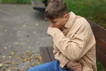 Fototapeta premium Young man suffering from stomachache and nausea outdoors. Space for text