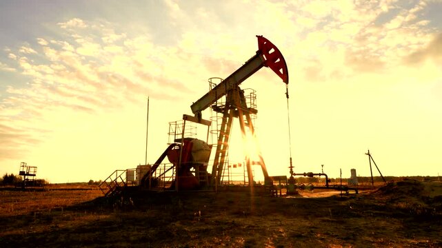 Pumpjack in oil well of oil field on sunset in Industrial crude area. Crude pump jack working on oil field. Pumpjack, Oil drill rig, drilling derrick in oilfield. Natural gas, Crude petroleum industry