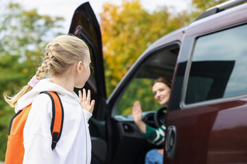 Mother taking her daughter to school near car outdoors, selective focus