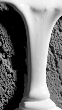 Extreme macro slow motion texture of thick white matte paint or resin slowly oozing and dripping down a rough textured gray wall or blank surface dripping, loop, matte