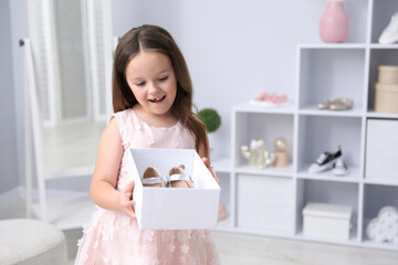 Little girl with pair of beautiful shoes in box at shop. Space for text