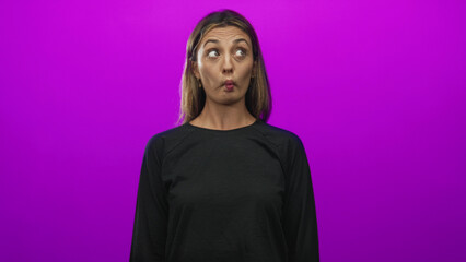 Fototapeta premium Woman purses lips and makes a fish face in a purple studio while glancing upward; playful curiosity imagination.