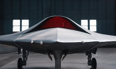 Front view of stealth drone. Military unmanned aircraft in hangar. Front part of satin grey drone with air inlet blocked with red cover.