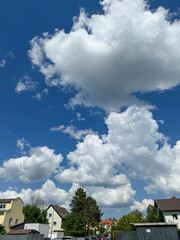 Bright blue sky with fluffy clouds over a residential area