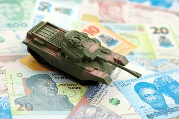 Nigerian naira currency money bills and toy tank close up. The concept of army funds and weapons...