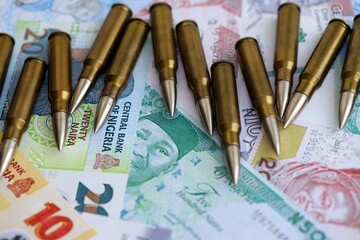 Nigerian naira currency money bills and rifle bullets close up. The concept of warfare and gun...