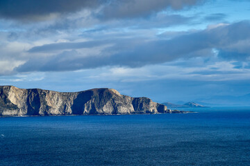 View over the ocean in cloudy blue sky weather with Achill island, Keel vilage and beach
