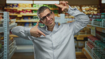 Man gesturing happily in a bright indoor supermarket with shelves full of products and colorful packaging, capturing a joyful shopping experience in a lively market setting.