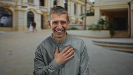 Smiling man outdoors, standing in a vibrant city street, showcasing a positive mood with historic...