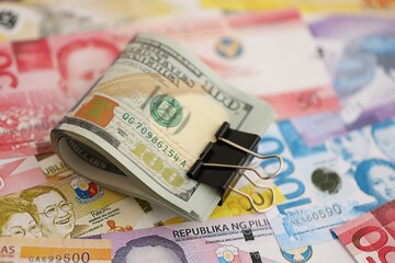 Philippines peso currency money bills and bunch of us dollar banknotes close up. The concept of economics and currency exchange
