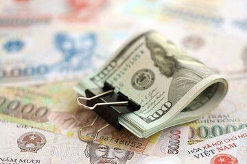 Vietnamese dong currency money bills and bunch of us dollar banknotes close up. The concept of economics and currency exchange