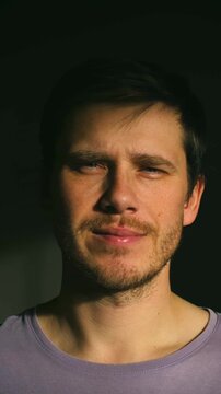 white man close-up under warm sunlight, subtle smile, soft stubble, lavender tee, dark background, gentle window light, intimate gaze, hopeful mood, lifestyle actor persona, content creator moments