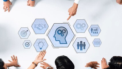 A diverse business team engages in a collaborative discussion over a table surrounded by conceptual icons symbolizing knowledge, creativity, and teamwork for innovative strategies. Raster