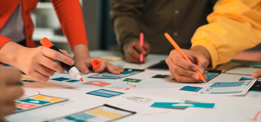 Diverse team members engage in a creative brainstorming session, using colorful markers to sketch ideas and develop innovative designs on a shared workspace. SACTR