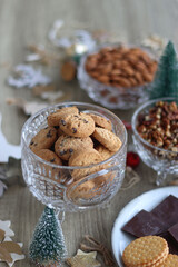 Various Christmas decorations, cookies, chocolate and nuts on wooden background. Selective focus.