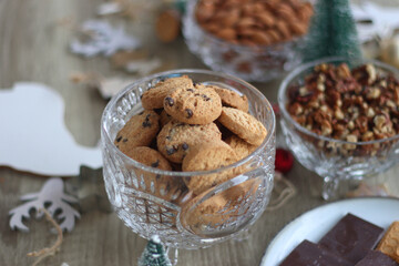 Various Christmas decorations, cookies, chocolate and nuts on wooden background. Selective focus.