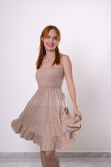 Naklejka premium Red-haired woman smiling while holding dress, joyful and feminine studio portrait.