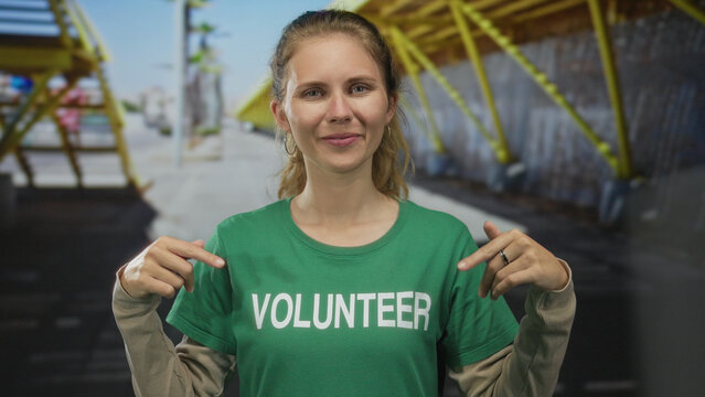 Woman wearing a shirt is pointing in a studio at volunteer blonde young wearing a tshirt and green earring. - Powered by Adobe
