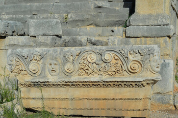 Historical stone bas-relief with carved faces in the ancient city of Myra, Demre, Antalya Province, Lycia, Turkey.