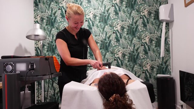 Professional beautician using a special device for radiofrequency treatment on a client's body for skin tightening and rejuvenation