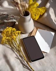 Cozy Flat Lay with Smartphone, Vase, Flowers, Note Card, and Fabric Background