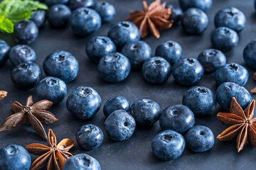 A pile of frozen blueberries rests on the deep black, displaying frost crystals that catch the light like tiny stars in the darkness