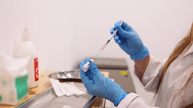 Professional cosmetologist in blue gloves preparing a syringe with an anti aging filler from a vial for a skin rejuvenation procedure