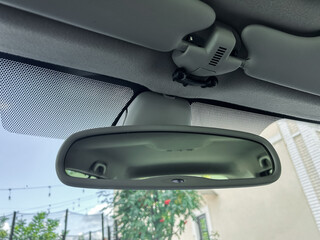 Reflecting on a sunny afternoon drive, the rearview mirror offers a glimpse of greenery and bright sky