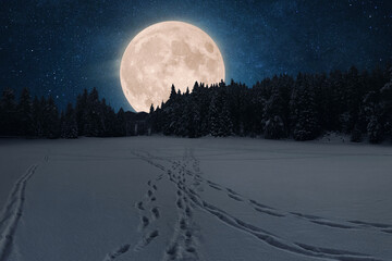 Full moon rising huge above a dark winter forest silhouette. Footprints trace a path across the snow-covered field under the light. Powerful, magical, and mystical night landscape. Winter Holidays.