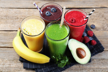 Different tasty smoothies in glasses and ingredients on wooden table, closeup