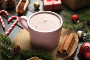 Tasty hot cocoa drink in cup and Christmas decor on wooden table, closeup