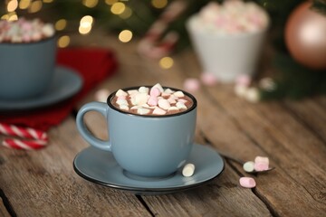 Tasty cocoa with marshmallows on wooden table against blurred Christmas lights, closeup
