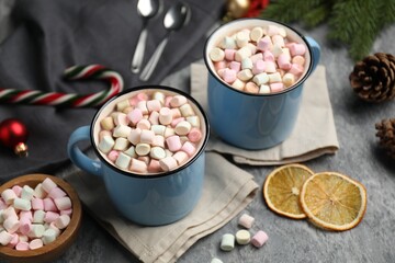 Tasty cocoa with marshmallows and Christmas decor on grey table, closeup