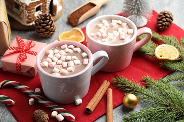 Tasty cocoa with marshmallows, cinnamon and Christmas decor on grey table, closeup