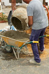 Obrero trabajando haciendo hormig&oacute;n con una hormigonera en la calle.